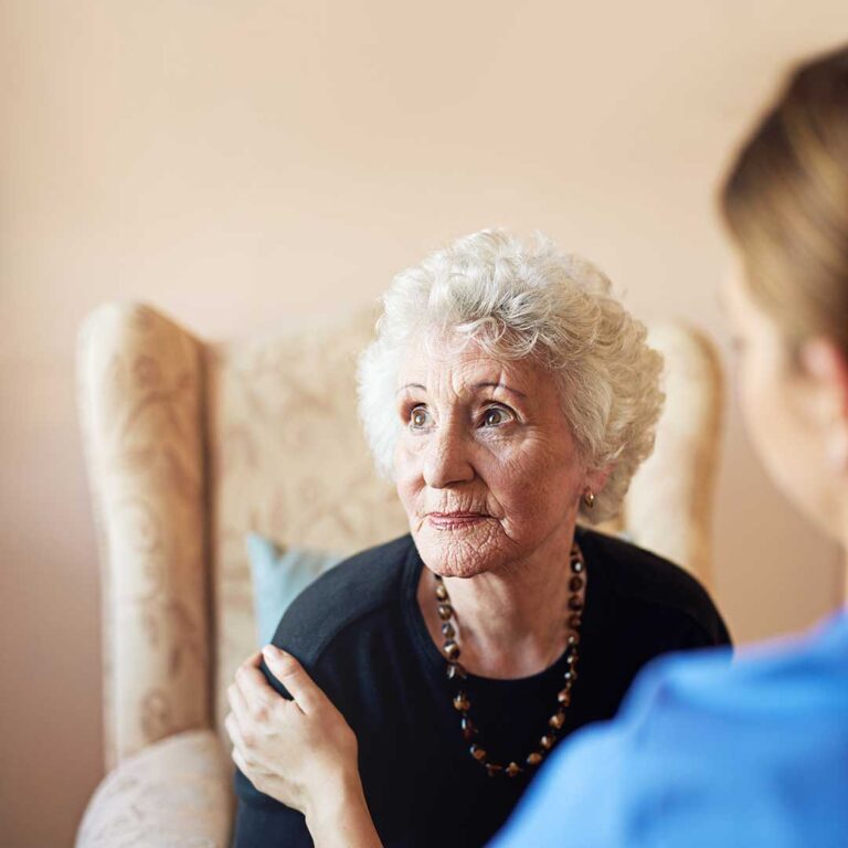 A staff member and senior resident reviewing a care plan together in a comfortable lounge area.